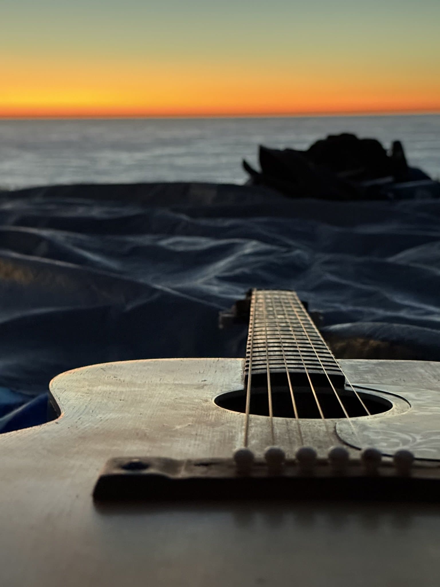 A guitar at the ocean's edge at dusk